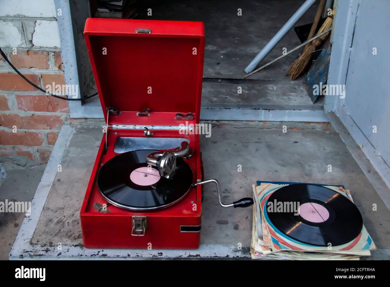 Alte rote vintage Plattenspieler mit Vinyl-Platte außerhalb des Hauses. Im Stil der alten Schule. Stockfoto