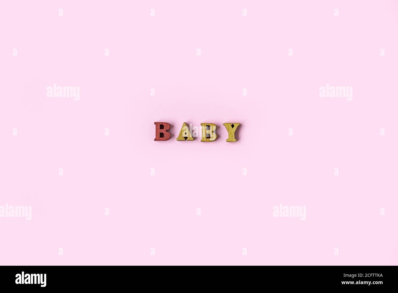 Das Wort BABY besteht aus Holzbuchstaben auf einem hellrosa Hintergrund. Bannerdesign. Babydusche-Konzept. Foto von minimalem Hintergrund mit beeautiful Stockfoto