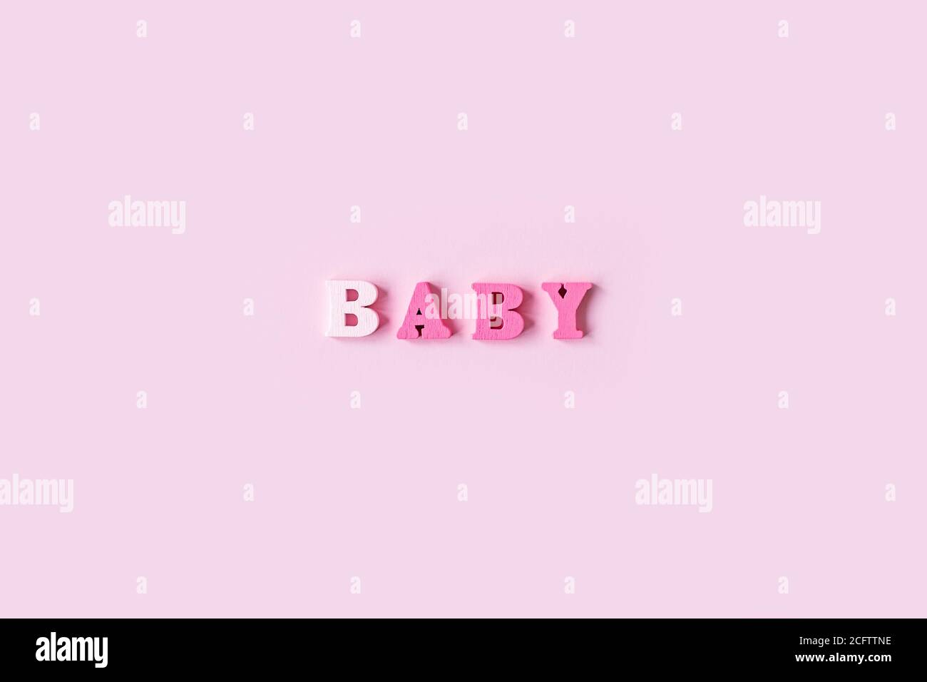 Das Wort BABY besteht aus Holzbuchstaben auf einem hellrosa Hintergrund. Bannerdesign. Babydusche-Konzept. Foto von minimalem Hintergrund mit beeautiful Stockfoto