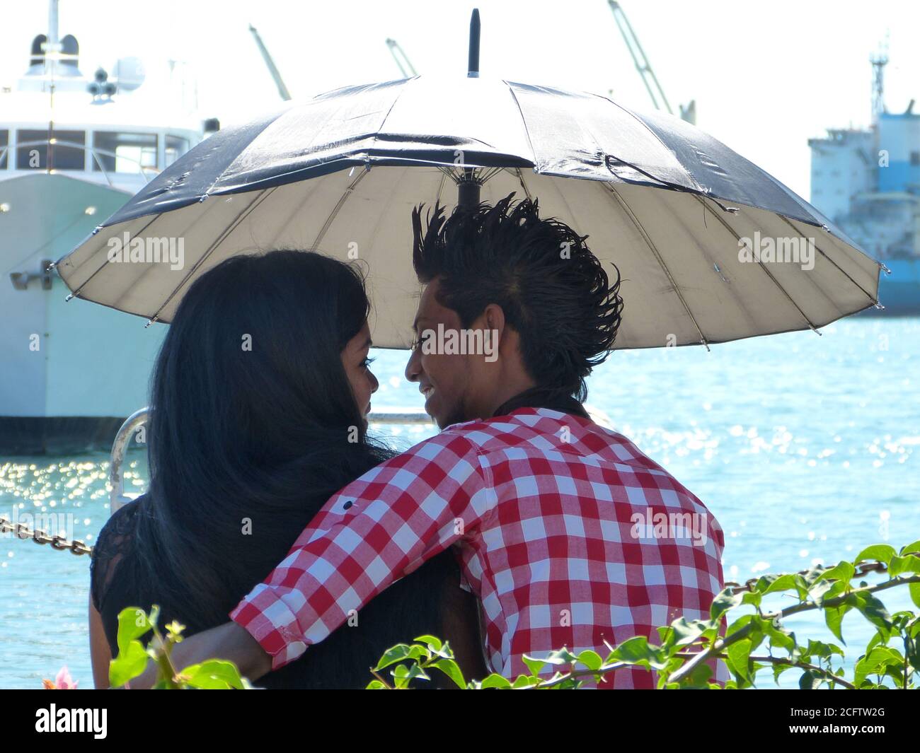 Glückliche junge Liebhaber am Ufer des Indischen Ozeans, Mauritius Insel. Mauritisches Mädchen und ein Mann unter dem Schirm. Valentinstag bei Maurice. Romantisches Date. Stockfoto