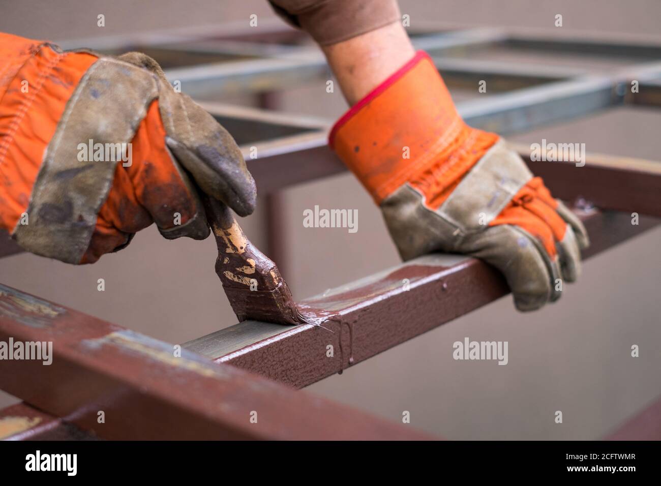 Hand des Auftragnehmers mit Pinsel, die Metallkonstruktion lackieren. Stockfoto