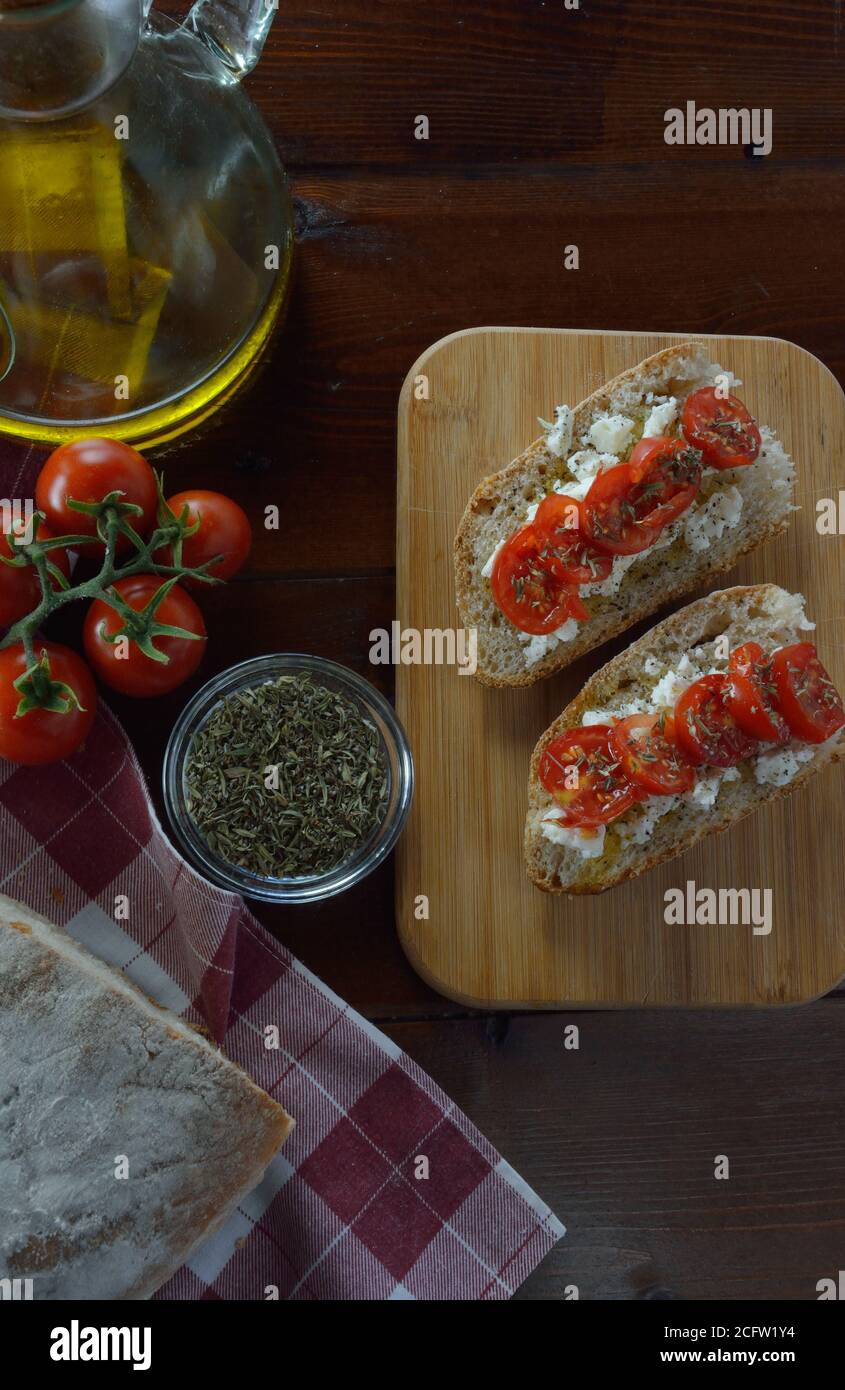 Bruschetta mit Kirschtomaten, Feta-Käse, Olivenöl, Knoblauch und Thymian auf Holzbrett Stockfoto