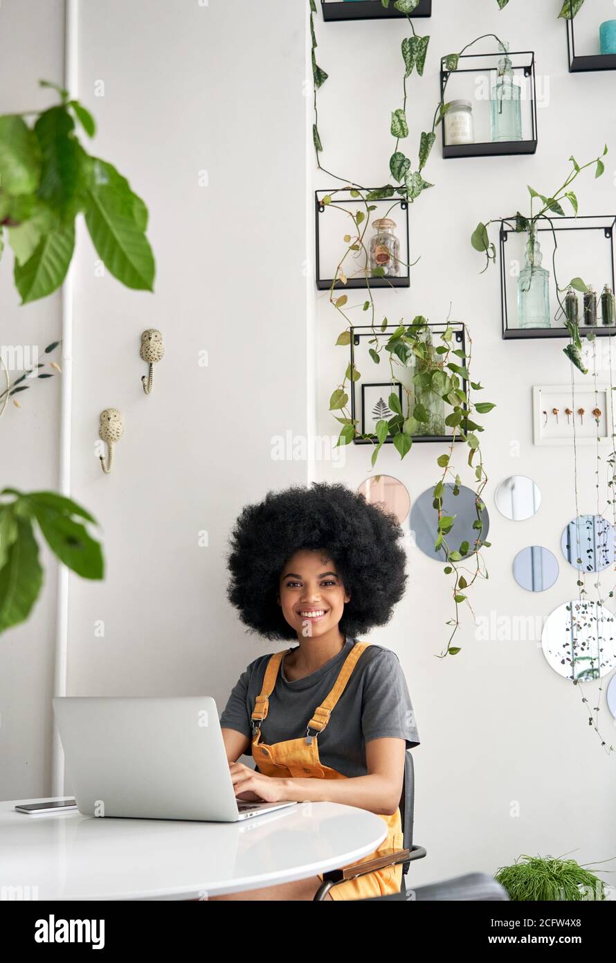 Glückliche afrikanische Dame Student mit Laptop sitzen am Tisch im Café Blick auf Kamera. Stockfoto