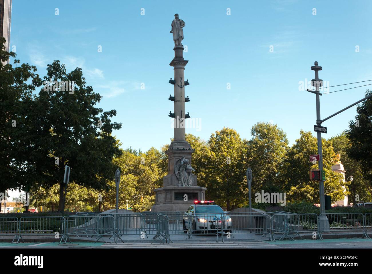 Statue von Columbus im Columbus Circle, bewacht von der Polizei der NYPD Autos und umgeben von Barrikaden, um Schäden aus jüngster Zeit zu verhindern Proteste Stockfoto