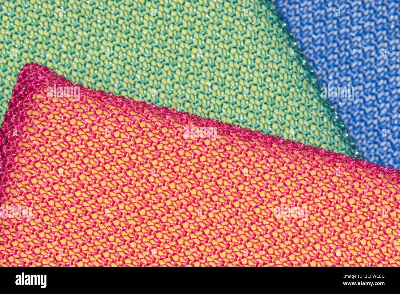 Bunte Putzschwämme mit flacher Lay-Anordnung. Nahaufnahme des Makrobilds mit Fokus auf der oberen roten Ebene und defokussierten Hintergrund. Stockfoto