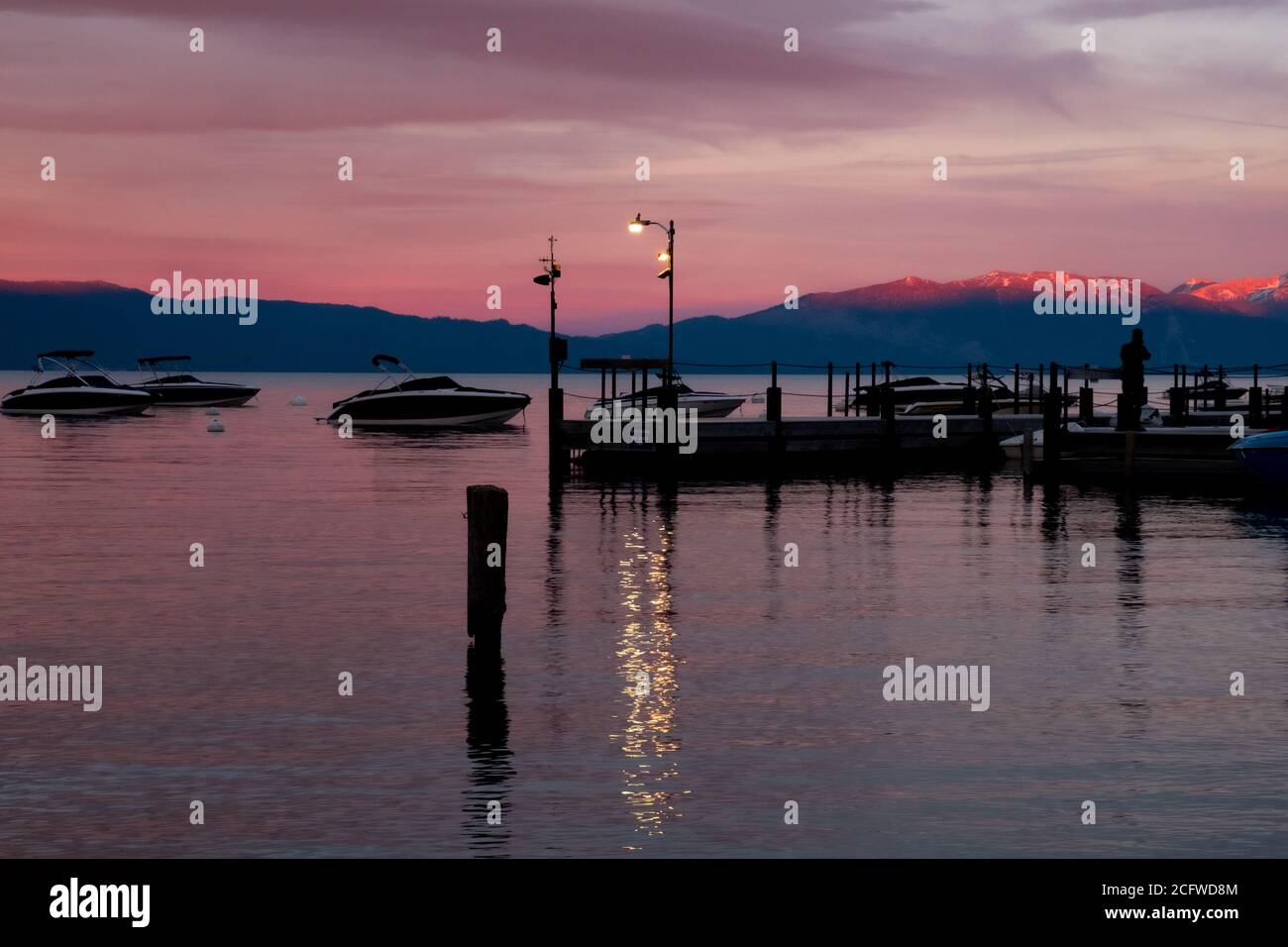 Später Sonnenuntergang am Lake Tahoe, Licht reflektiert auf den Bergen dahinter, Boote und Menschen in Silhouette Stockfoto