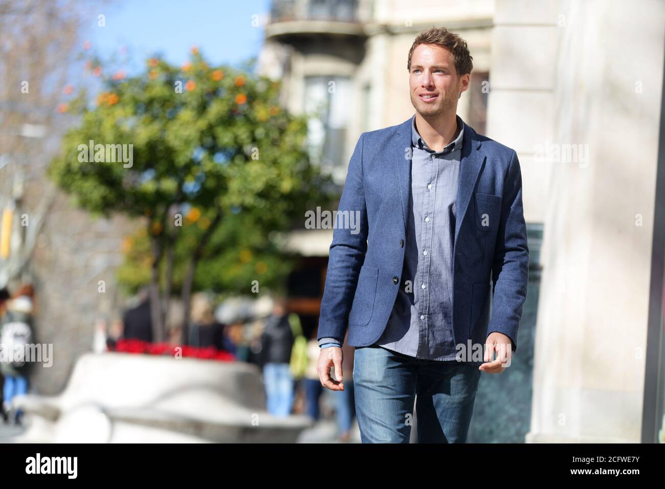 Schöner junger Geschäftsmann, der morgens auf der Stadtstraße zur Arbeit geht, trägt ein elegantes Freizeitoutfit aus Wollanzug und blauer Jeans. Stadt Stockfoto