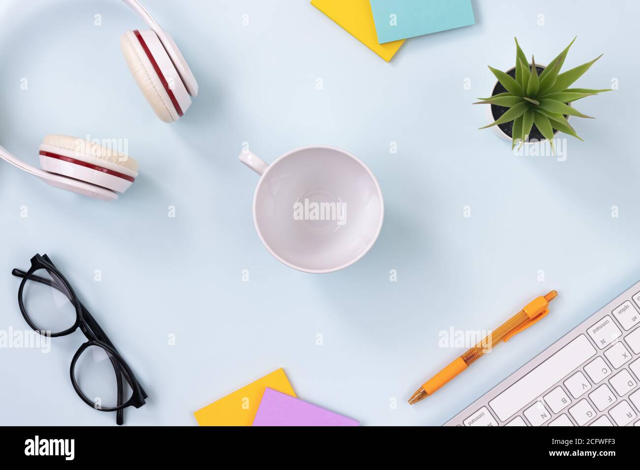 Center-Kaffeetasse und Bürobedarf als Tastatur, Kopfhörer, Stift, Haftnotiz, Büropflanzen, Gläser Auf dem modernen sauberen kreativen Schreibtisch oder Tisch auf der Oberseite Stockfoto