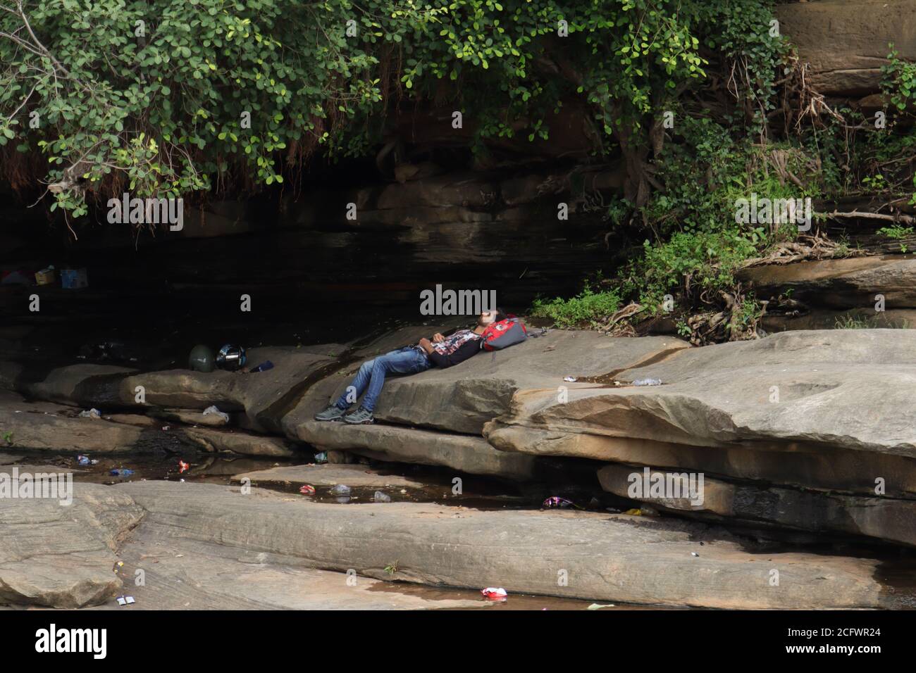 Bokeh-Aufnahme eines fließenden Wasserfalls mit selektivem Fokus und Baumhintergrund. Kleine Kinder baden im gefährlichen Wasserfall in Mirzapur, Indien w Stockfoto