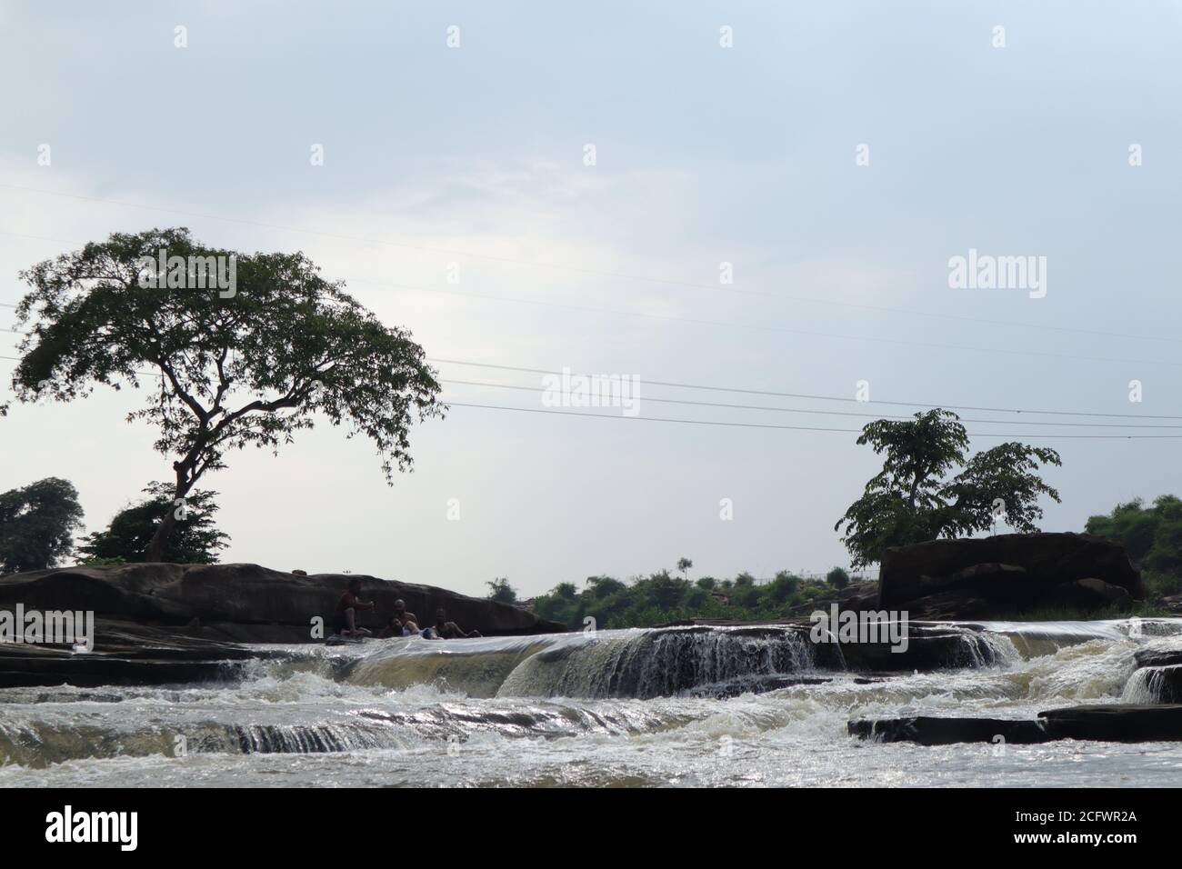 Bokeh-Aufnahme eines fließenden Wasserfalls mit selektivem Fokus und Baumhintergrund. Kleine Kinder baden im gefährlichen Wasserfall in Mirzapur, Indien w Stockfoto