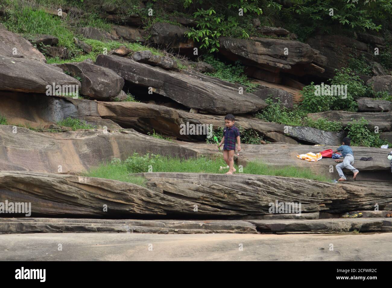 Bokeh-Aufnahme eines fließenden Wasserfalls mit selektivem Fokus und Baumhintergrund. Kleine Kinder baden im gefährlichen Wasserfall in Mirzapur, Indien. Stockfoto