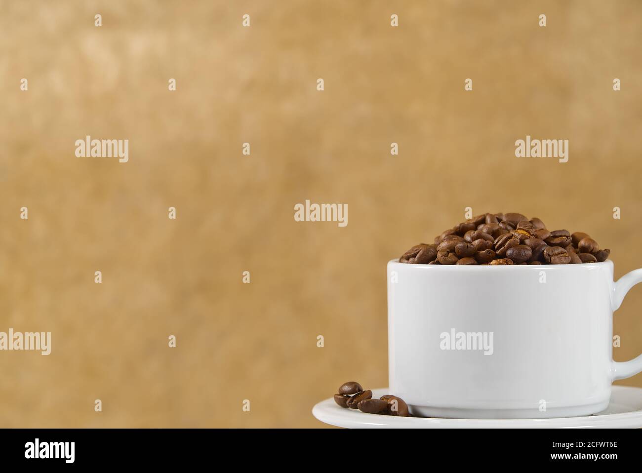 Internationaler Tag des Kaffees Konzept. Nahaufnahme weiße Kaffeetasse voller Kaffeebohnen auf beigem Hintergrund. Stockfoto