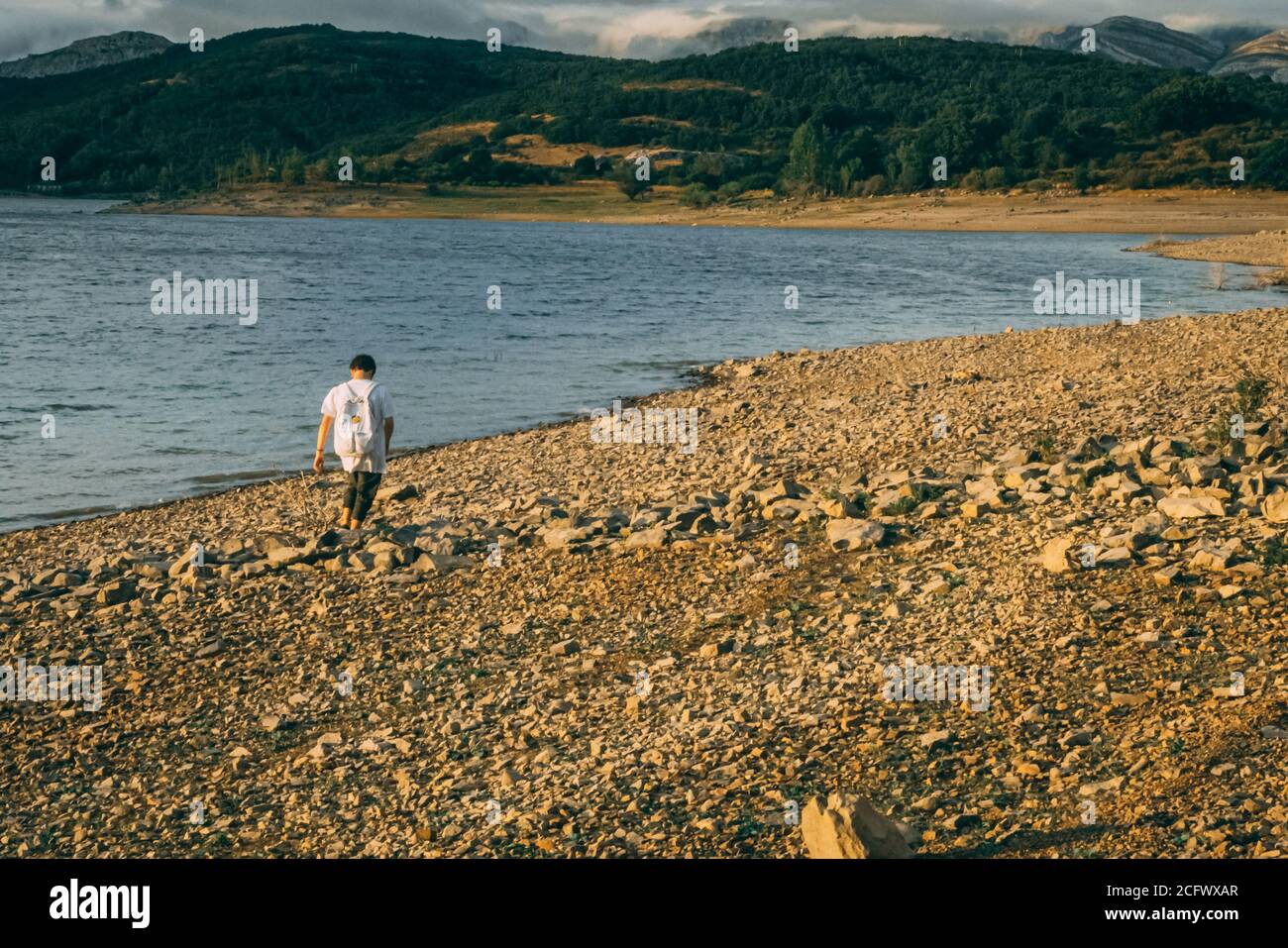 Junger Teenager, der alleine am See spazieren geht. Stockfoto