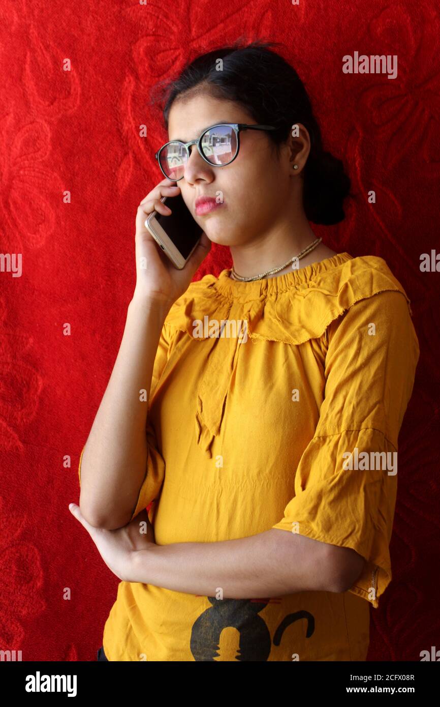 Beauty Mode Porträt. Ernst unglückliche Frau sprechen am Telefon und tragen gelbe Spitze, traurige Frauen auf Abruf über roten Hintergrund, selektive Fokus mit Unschärfe. Stockfoto