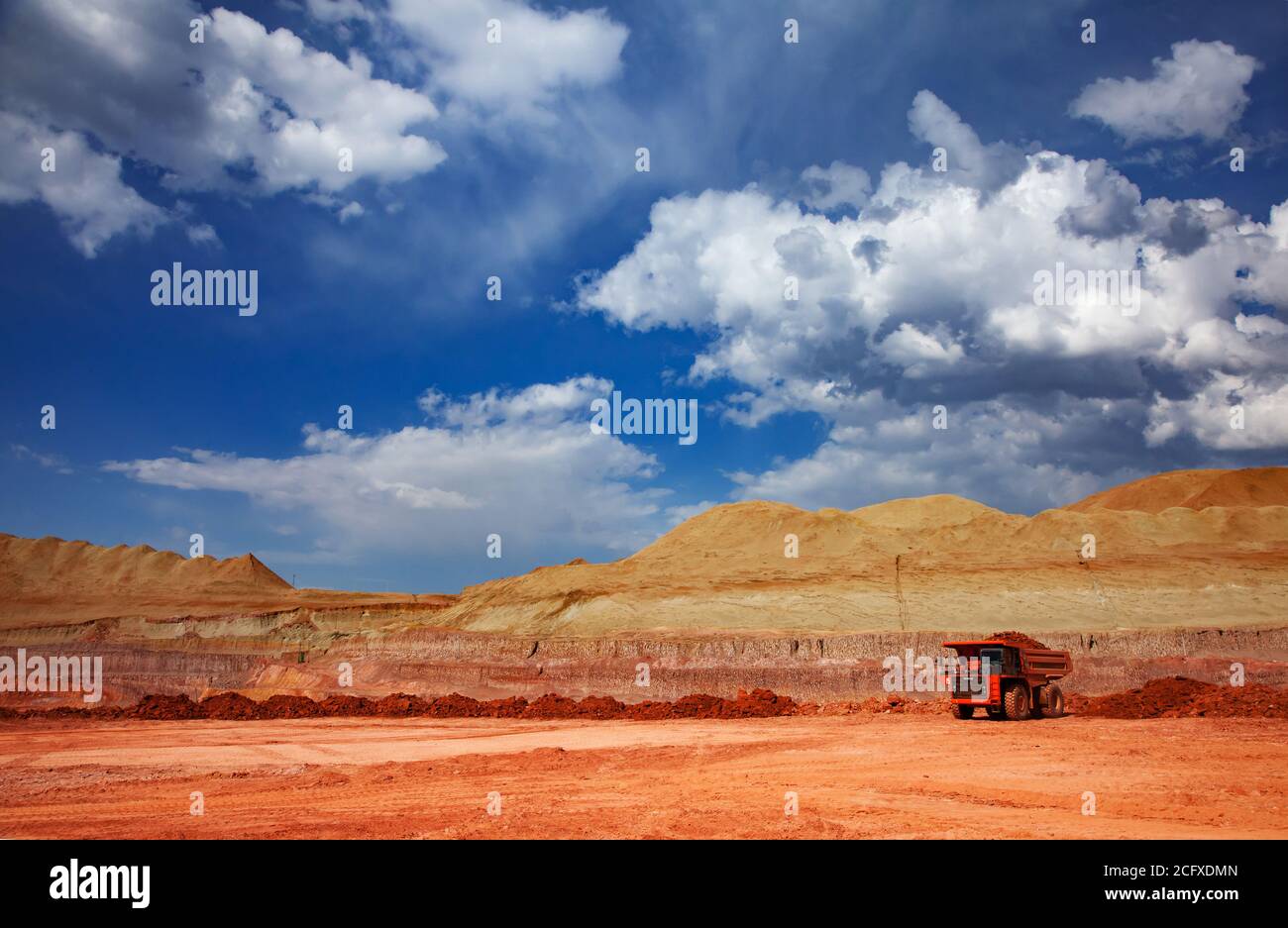 Aluminiumerz Bergbau und Transport. Steinbruch aus Bauxit. Tagebau. Orange Hitachi Steinbruch Kipper. Am blauen Himmel mit Wolken. Stockfoto