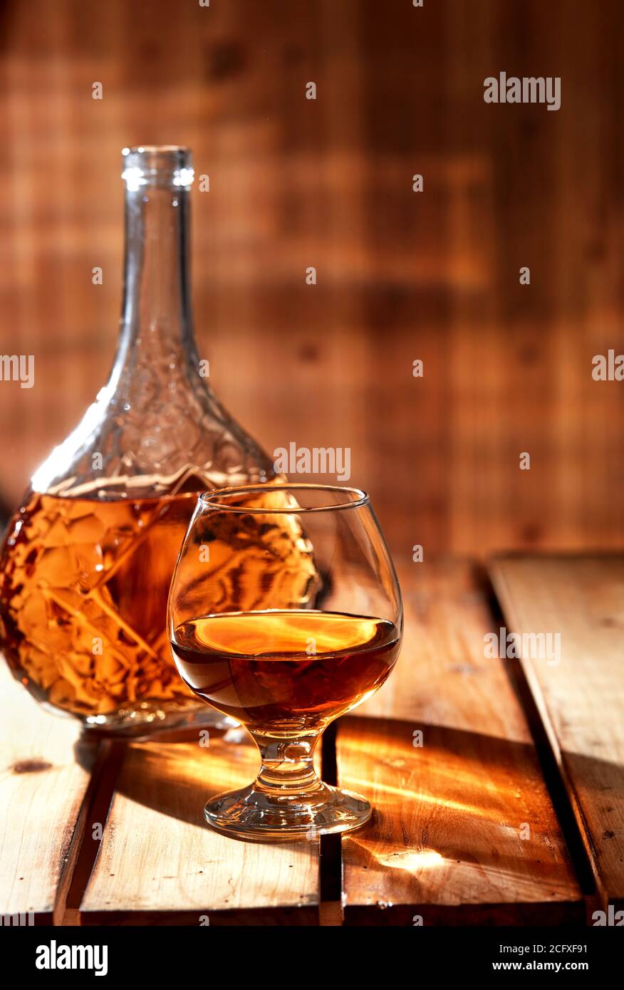 Glas und Flasche Cognac auf altem Holztisch Stockfoto