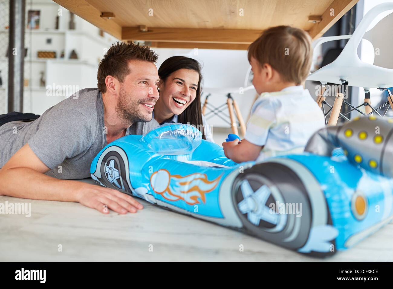 Lachende Eltern spielen mit ihrem Sohn im aufblasbaren Kinderzimmer Auto als Schlauchboot aus Gummi Stockfoto