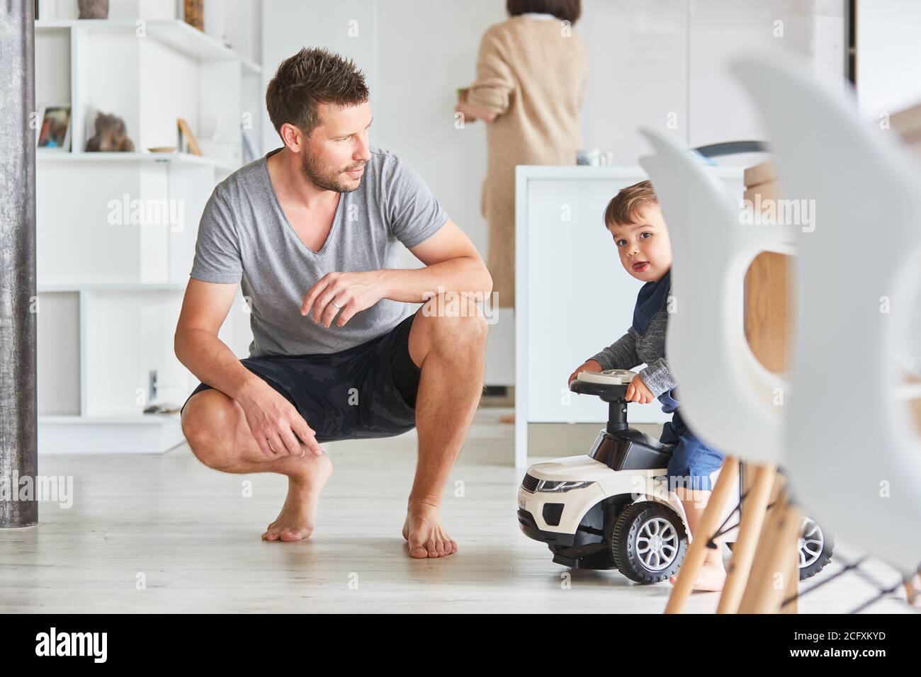 Vater und Kind mit Schubauto als Kinderfahrzeug Zu Hause im Wohnzimmer Stockfoto