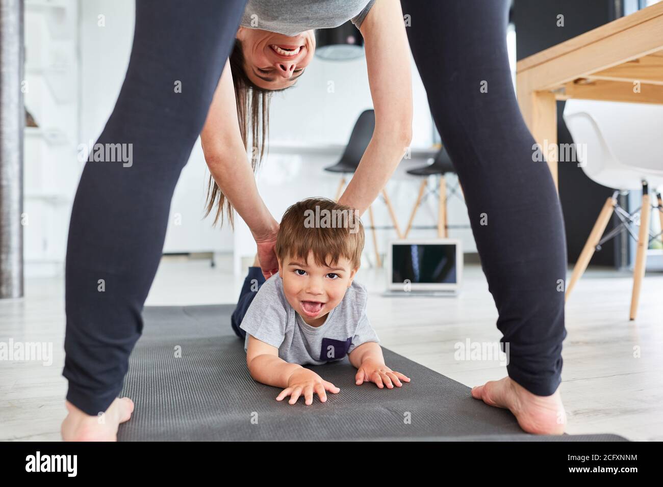 Mutter hilft Kind spielen und Gymnastik auf der Übung Matte im Wohnzimmer Stockfoto