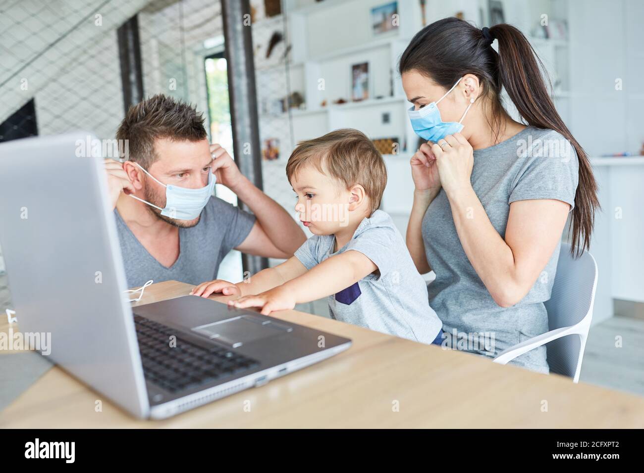 Familie mit kleinem Kind trägt Mund und Nase Schutz gegen Coronavirus und Covid-19 Stockfoto