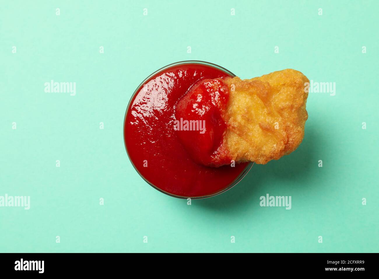 Einzelne Chicken Nuggets mit Ketchup auf Minze Hintergrund Stockfoto