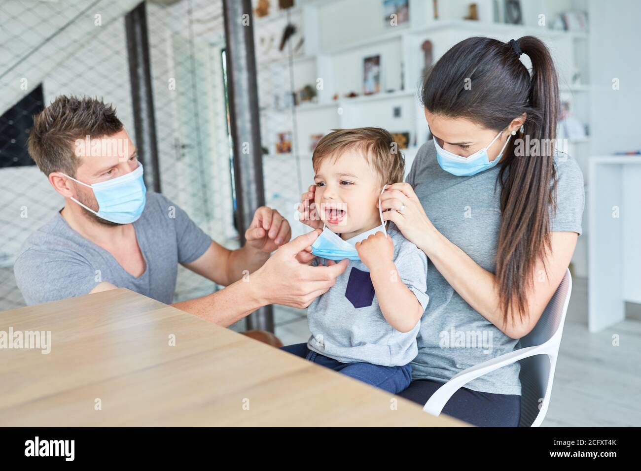 Eltern und weinendes Kind mit Mund- und Nasenschutz weil Von Coronavirus und Covid-19 Stockfoto