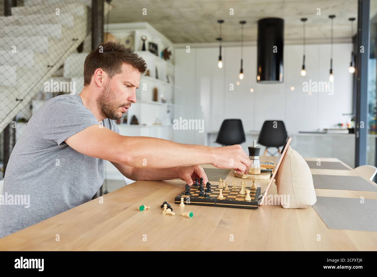 Konzentrierter Mann, der zu Hause im Video-Chat Schach spielt Im Wohnzimmer Stockfoto