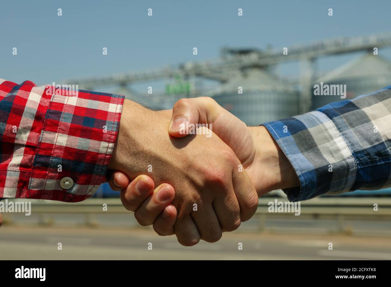 Geschäftsleute schütteln die Hände gegen Silos. Agrarwirtschaft Stockfoto