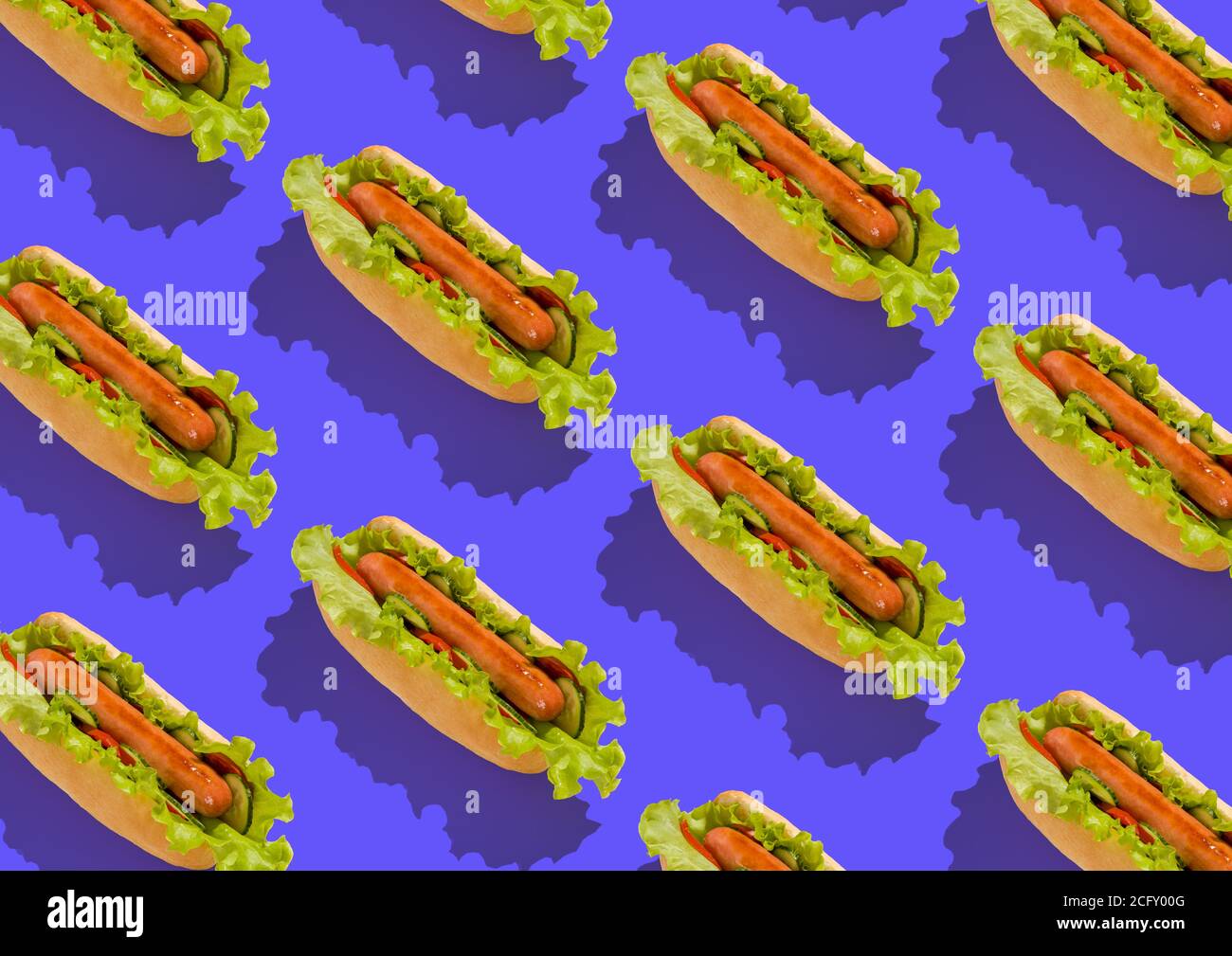 Amerikanischer Hot Dog mit Salat, Tomaten und Gurken auf blauem Hintergrund Stockfoto