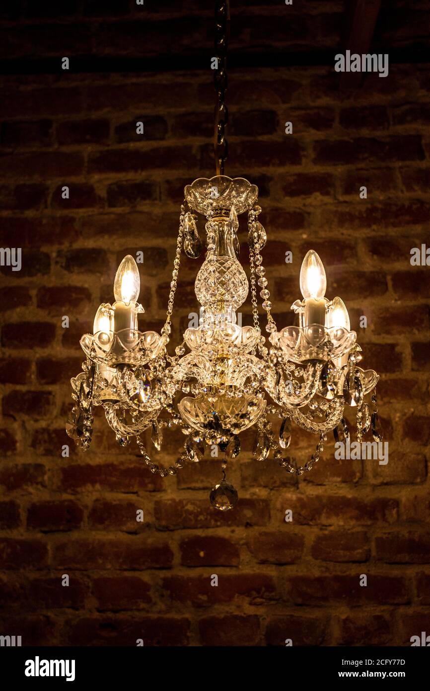 Kristall-Kronleuchter, antike Lampe auf dem Hintergrund der braunen Ziegelwand. Stockfoto
