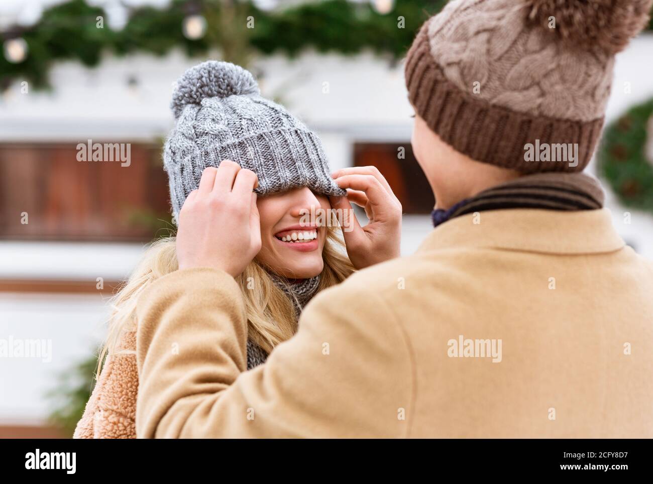 Romantisches Paar mit Spaß im Freien im Winter, Mann spielt mit Freundin Hut Stockfoto