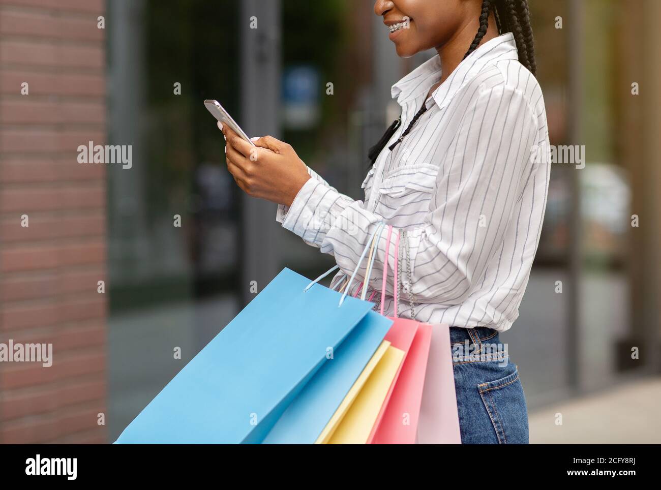 Bestes Angebot von Geschäften. Glückliche afroamerikanische Frau mit Taschen verlassen Bewertungen des Geschäfts Stockfoto