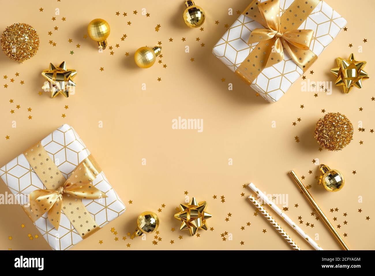 Weihnachtskomposition. Rahmen aus goldenen Weihnachtsdekorationen und Luxus-Geschenkboxen auf gelbem Hintergrund. Flach liegend, Draufsicht, Kopierbereich. Greeti würzen Stockfoto