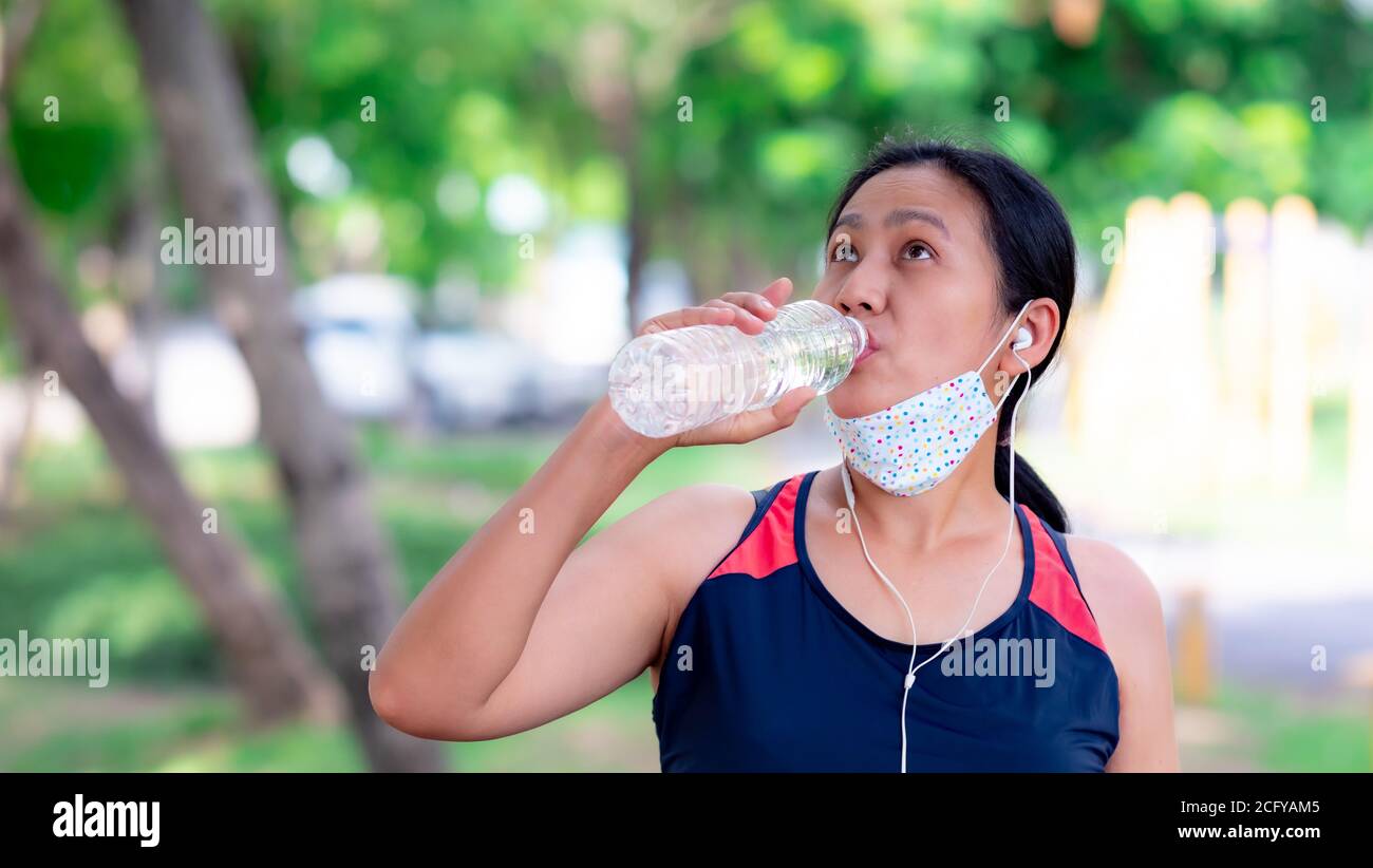 Portrait von Frauen aus Asien, die nach dem Joggen reines Wasser trinken Der Park Stockfoto