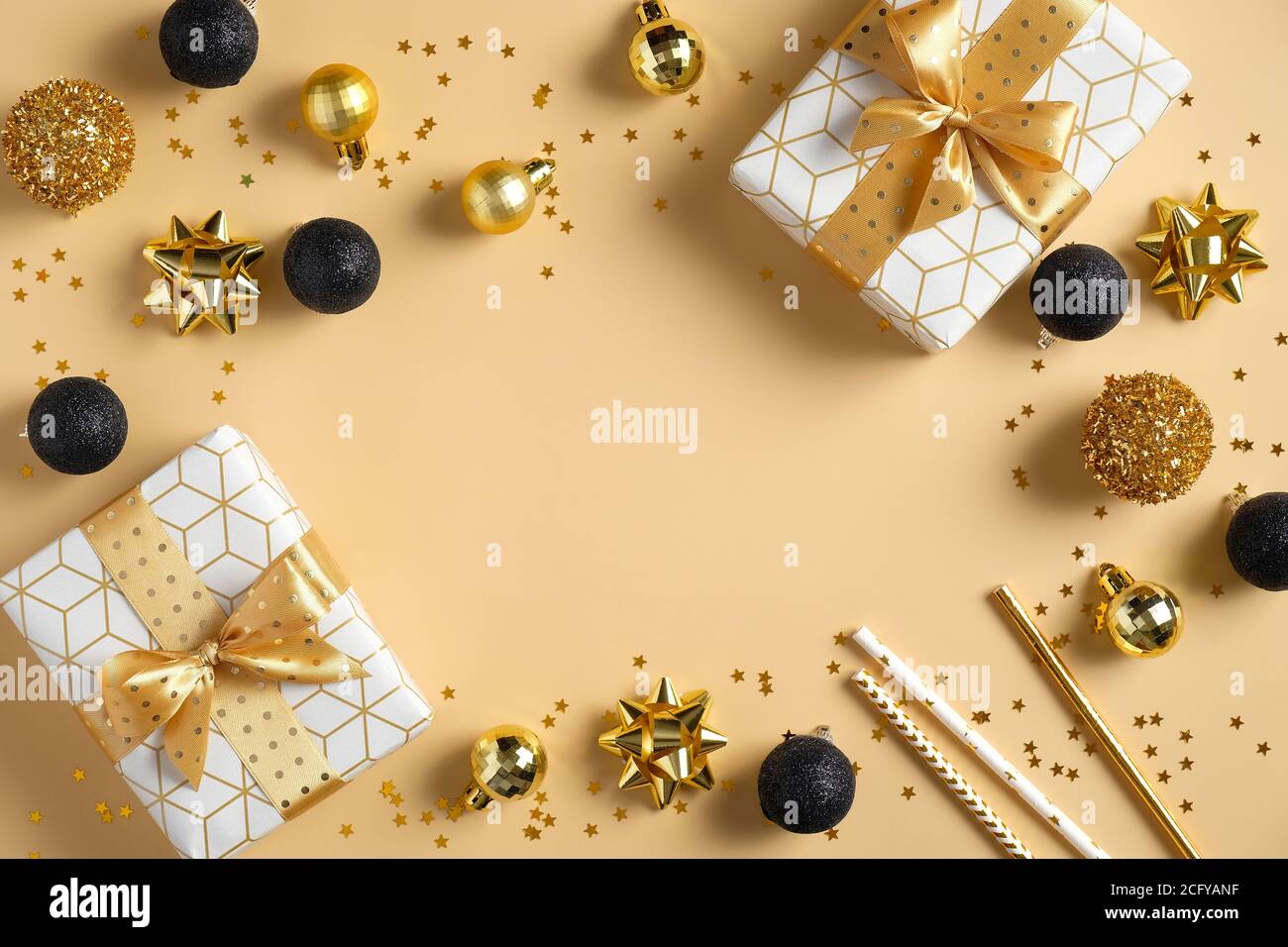 Moderne Weihnachtskomposition. Rahmen aus luxuriösen Geschenkboxen, schwarzen und goldenen Kugeln Dekorationen, Konfetti-Sterne auf gelbem Hintergrund. Flach liegend, oben Stockfoto