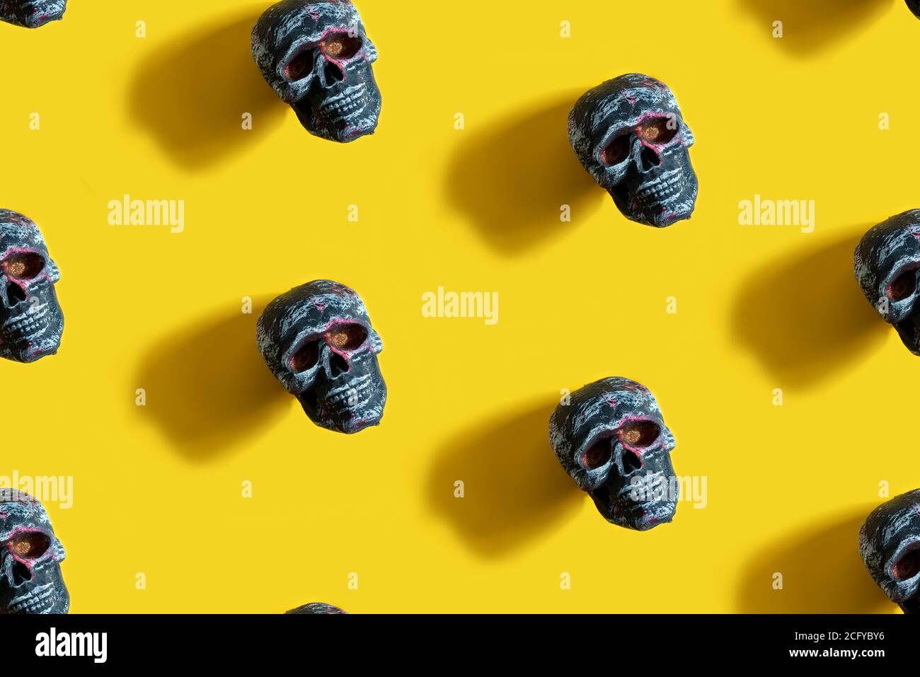 Nahtloses Muster Halloween Party Hintergrund mit menschlichen Schädel auf einem gelben Hintergrund mit langen Schatten und Kopierraum. Draufsicht. Stockfoto