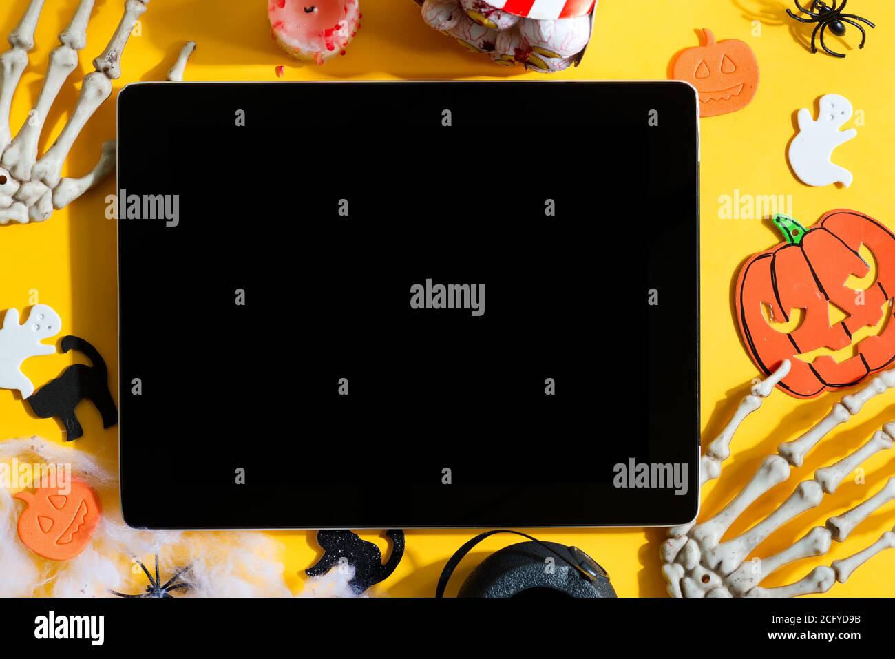 Dekoration Happy Halloween Hintergrund mit Zubehör - Schnitt handgemachte Kürbisse und Fledermäuse, Skelett Hände und Tablet für Text auf gelbem Hintergrund. Stockfoto