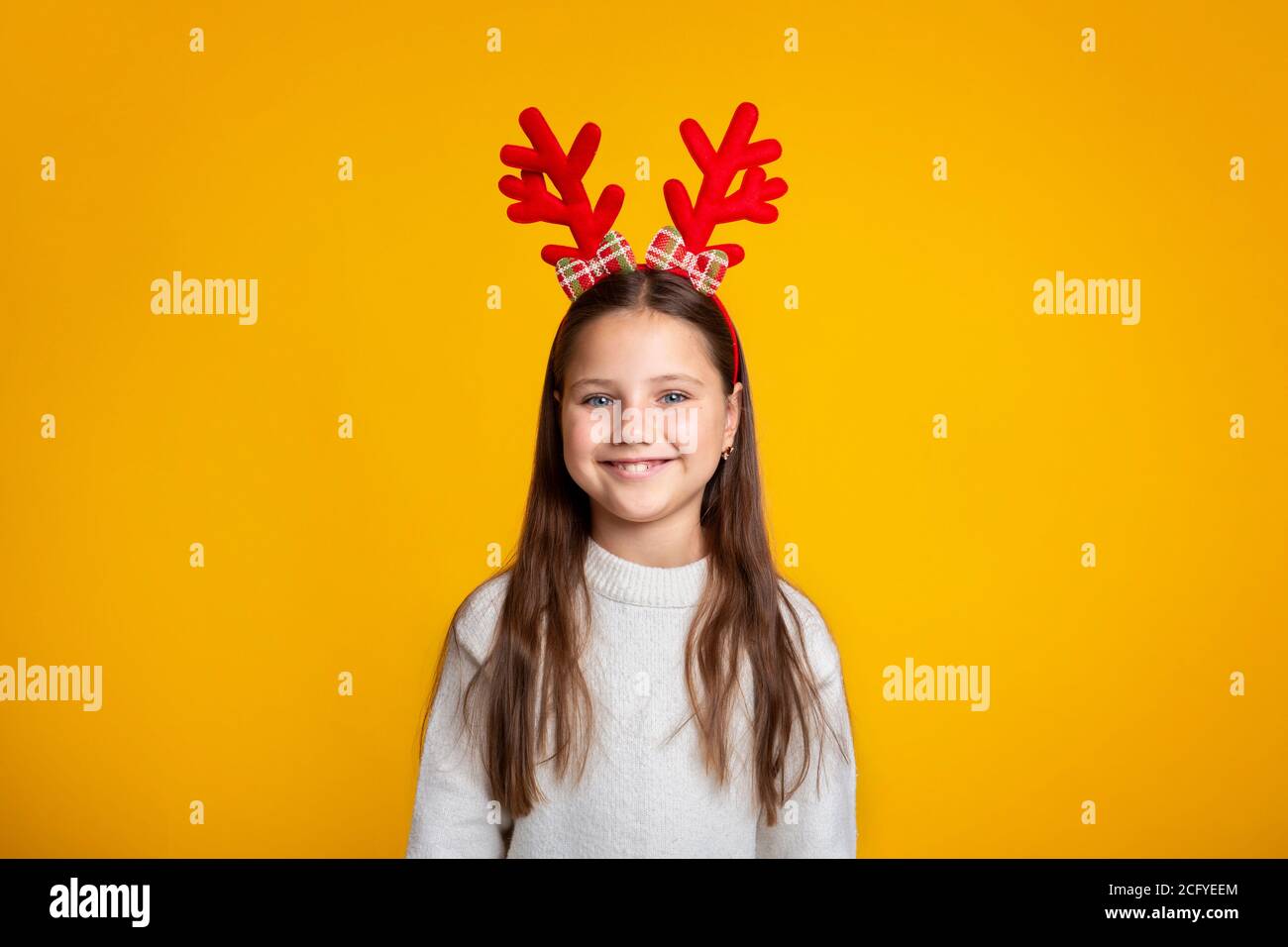 Kindheit und Kinder bei Weihnachten Konzept. Fröhliches kleines Kind mit Hörnern und Pullover Stockfoto