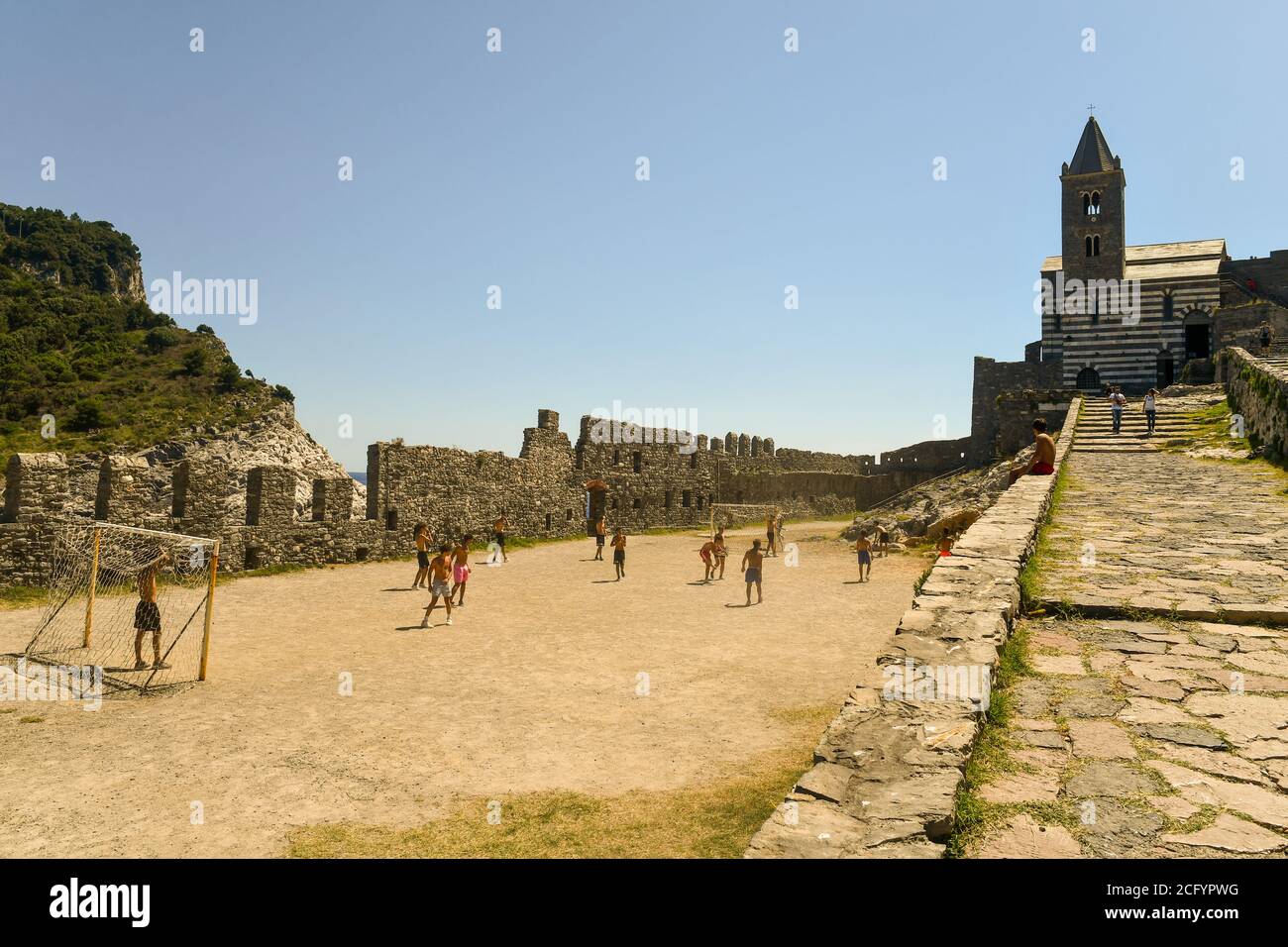 Eine Gruppe von Jungen, die an einem Sommertag im Kirchhof der berühmten gotischen Kirche St. Peter Fußball spielen, Porto Venere, La Spezia, Ligurien, Italien Stockfoto