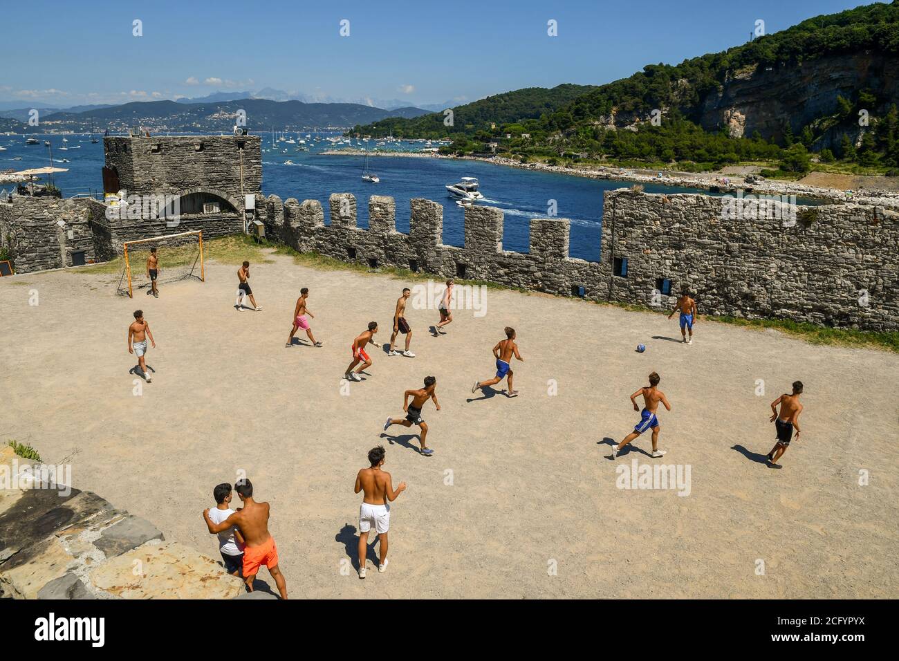 Eine Gruppe von Jugendlichen spielt Fußball im Park der Kirche St. Peter mit der Insel Palmaria im Hintergrund, Porto Venere, La Spezia, Italien Stockfoto