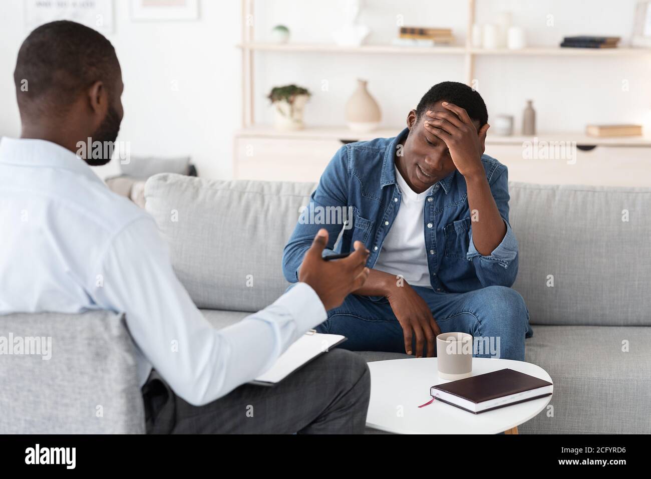 Psychotherapie-Konzept. Depressiver schwarzer Mann im Gespräch mit Psychologen während der individuellen Therapie Stockfoto