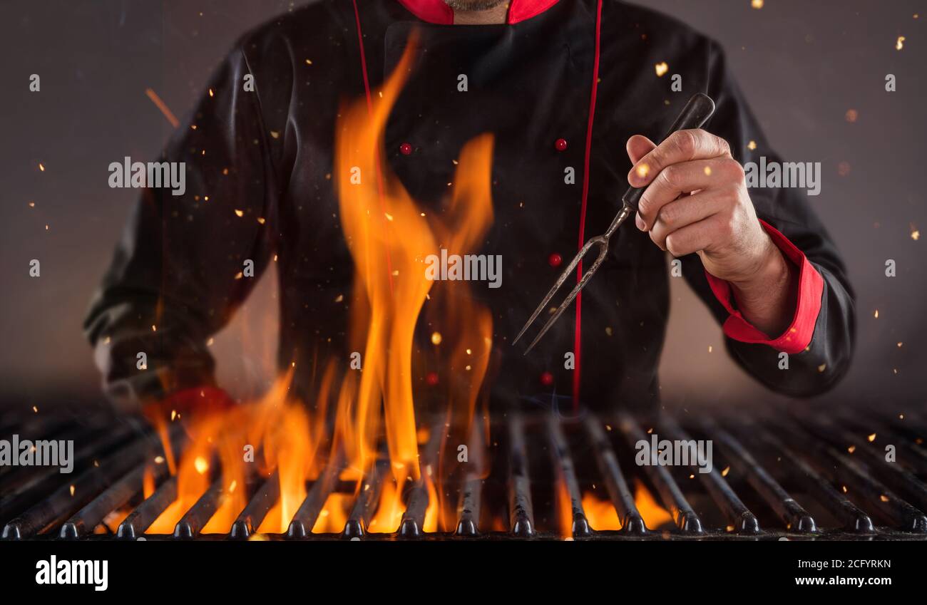 Nahaufnahme des Küchenchefs, der die Gabel über dem Grill hält. Konzept der Lebensmittelzubereitung, bereit für die Produktplatzierung. Stockfoto