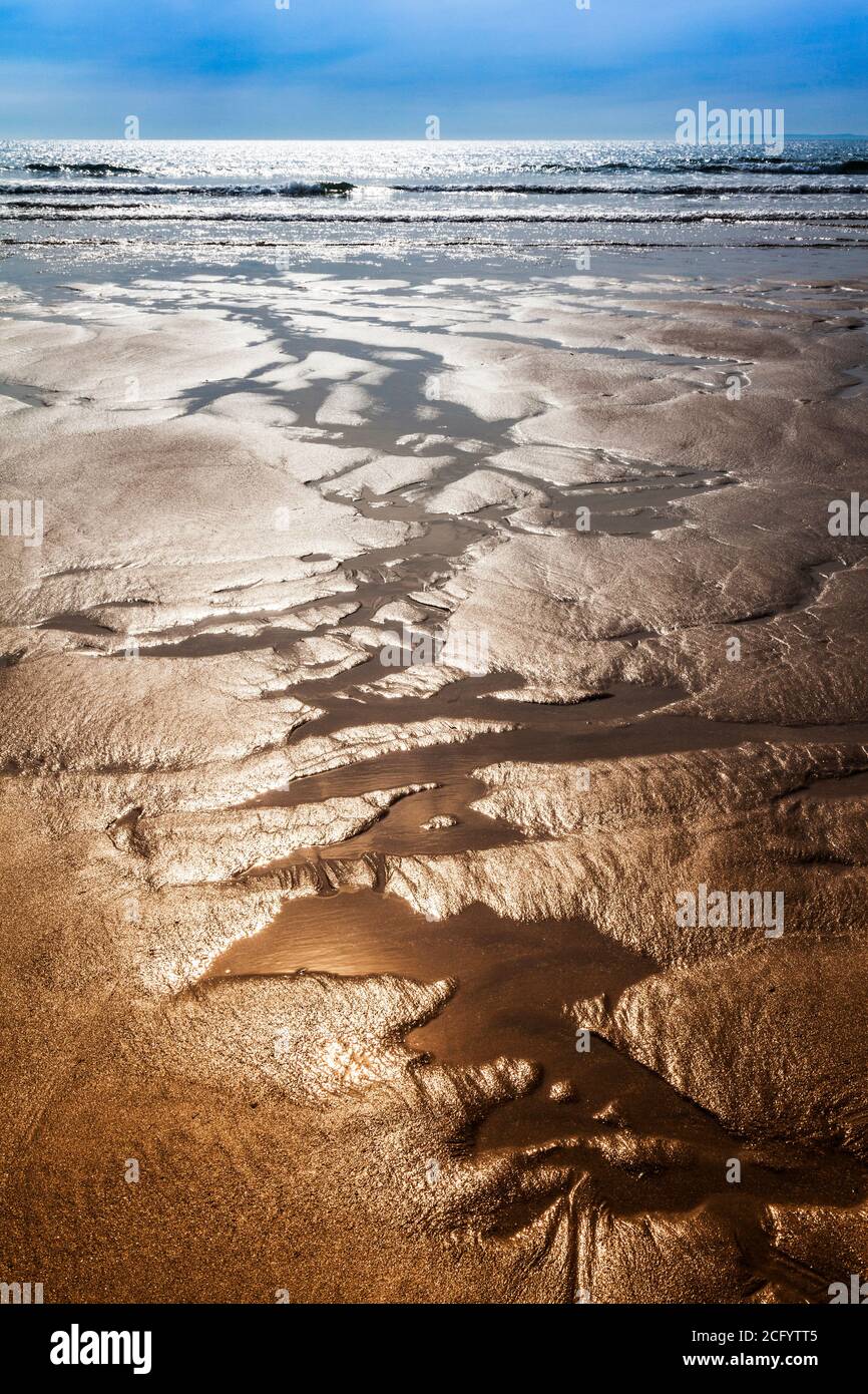 Die glitzernden Sand Bäche bilden abstrakte Muster am Strand. Stockfoto