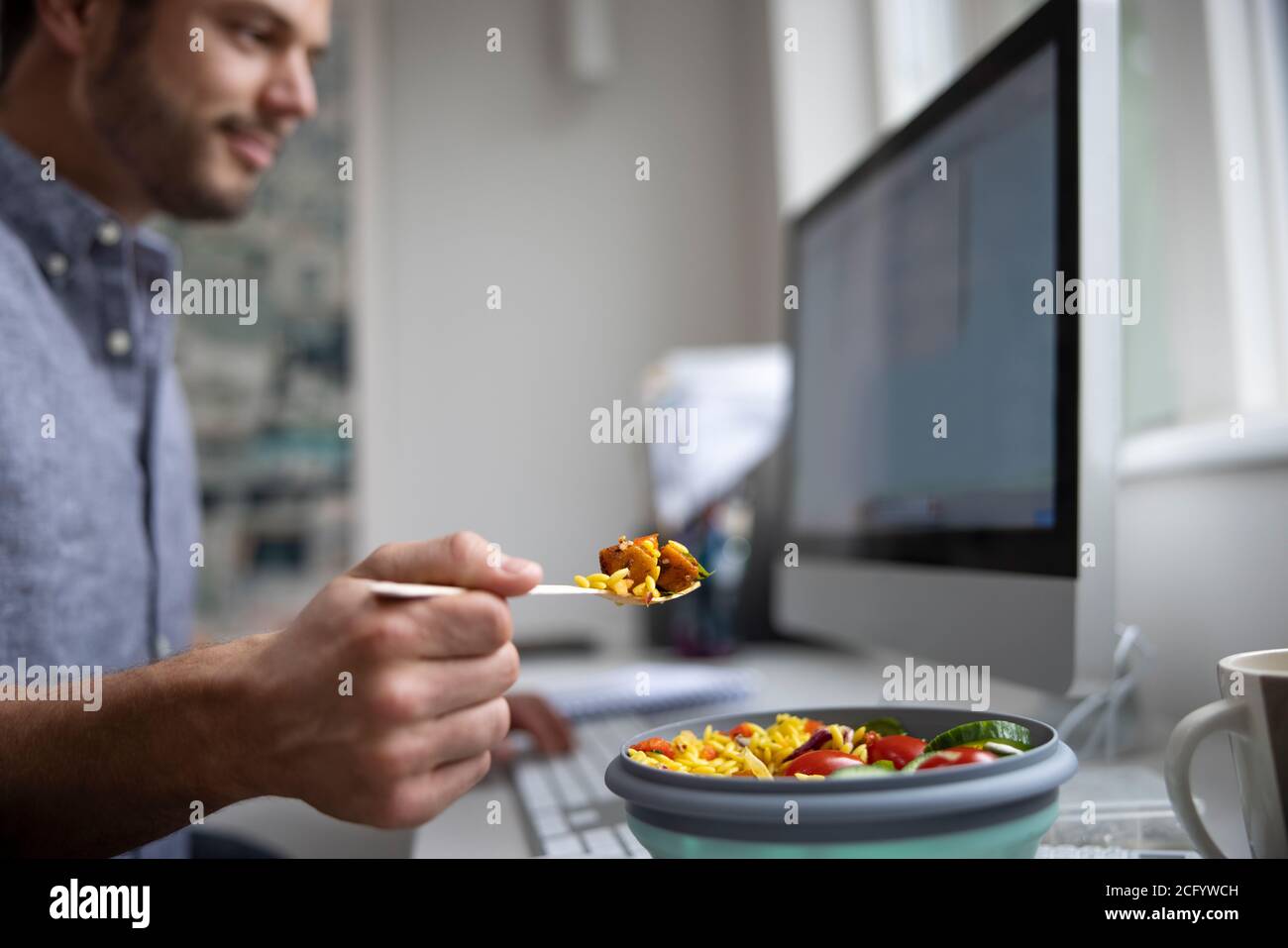 Männliche Arbeiter Im Büro Mit Gesunden Vegan Mittagessen An Der Rezeption Stockfoto