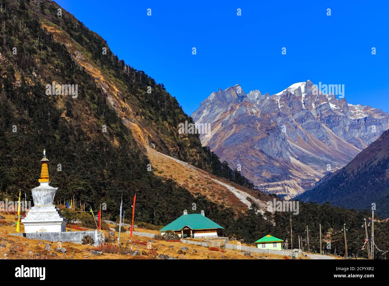 Tibetische Stupa und Gebetsfahne mit hohen Bergketten in Der Hintergrund hinten beleuchtet mit Sonne im Tal von Blumen in Sikkim Indien Stockfoto