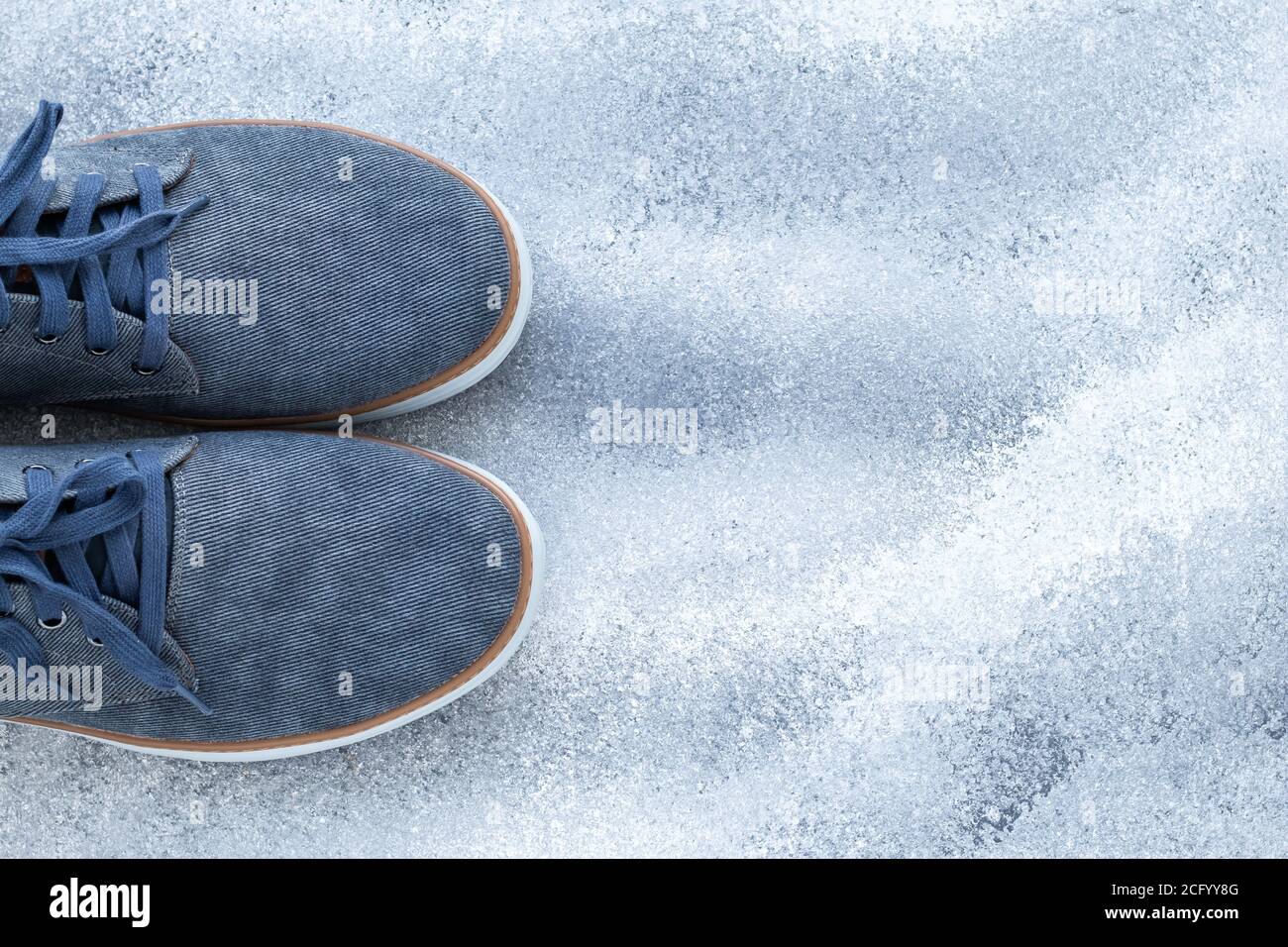 Ein Paar Herrenschuhe, blaue Jeansschuhe auf grauem Hintergrund. Bequeme Textilschuhe. Draufsicht. Lässiges Modekonzept. Leerer Platz für Stockfoto