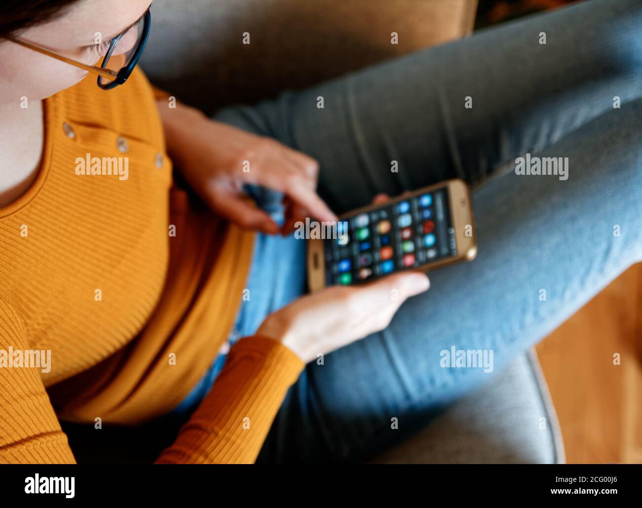 Nahaufnahme der jungen Frau von oben mit Smartphone an Home gelb orange Farben Stockfoto