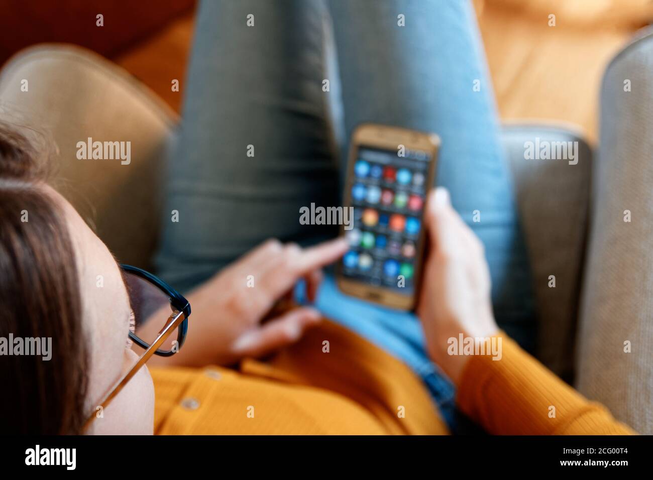 Nahaufnahme der jungen Frau von oben mit Smartphone an Home gelb orange Farben Stockfoto