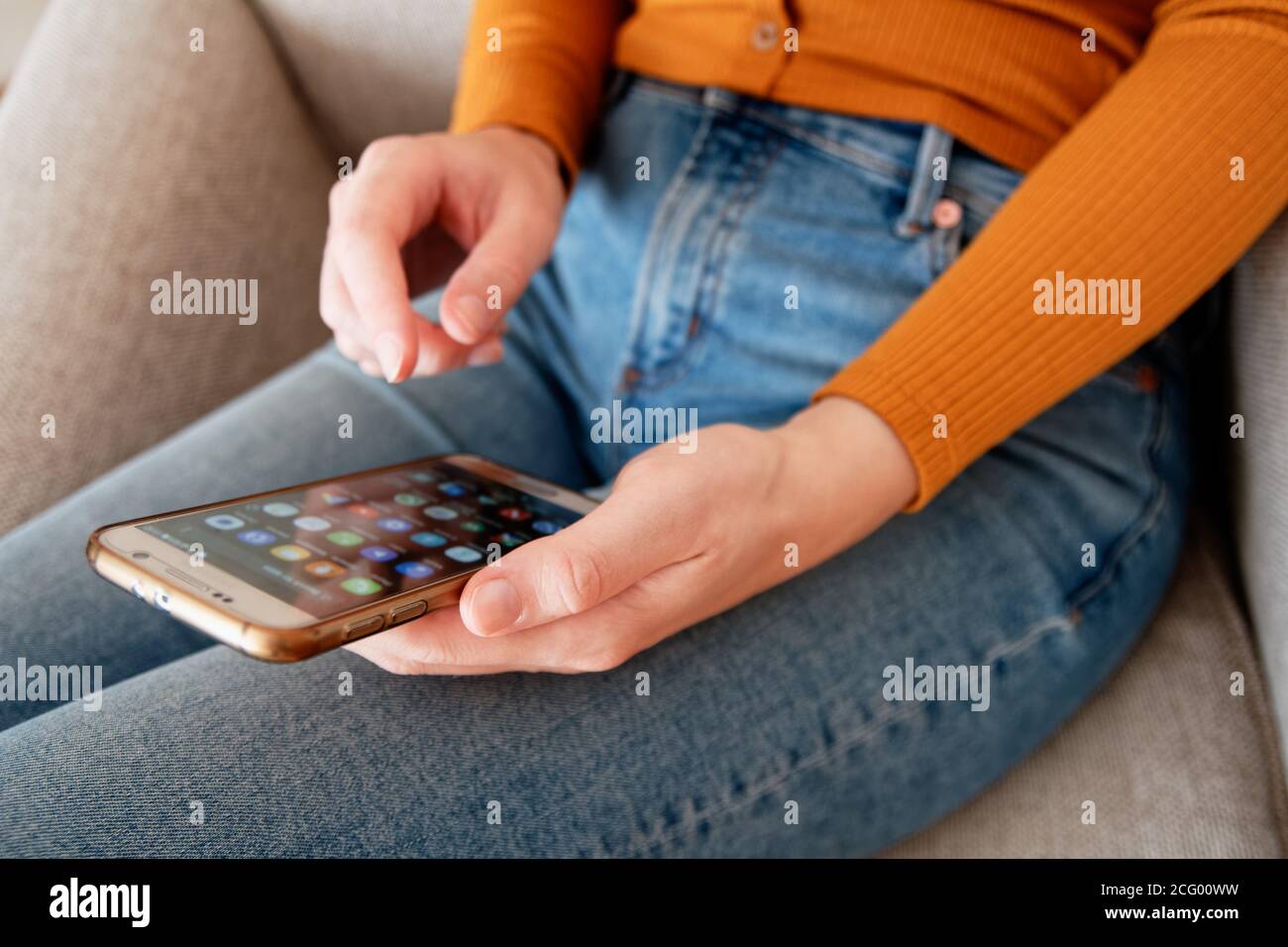 Nahaufnahme der jungen Frau von oben mit Smartphone an Home gelb orange Farben Stockfoto