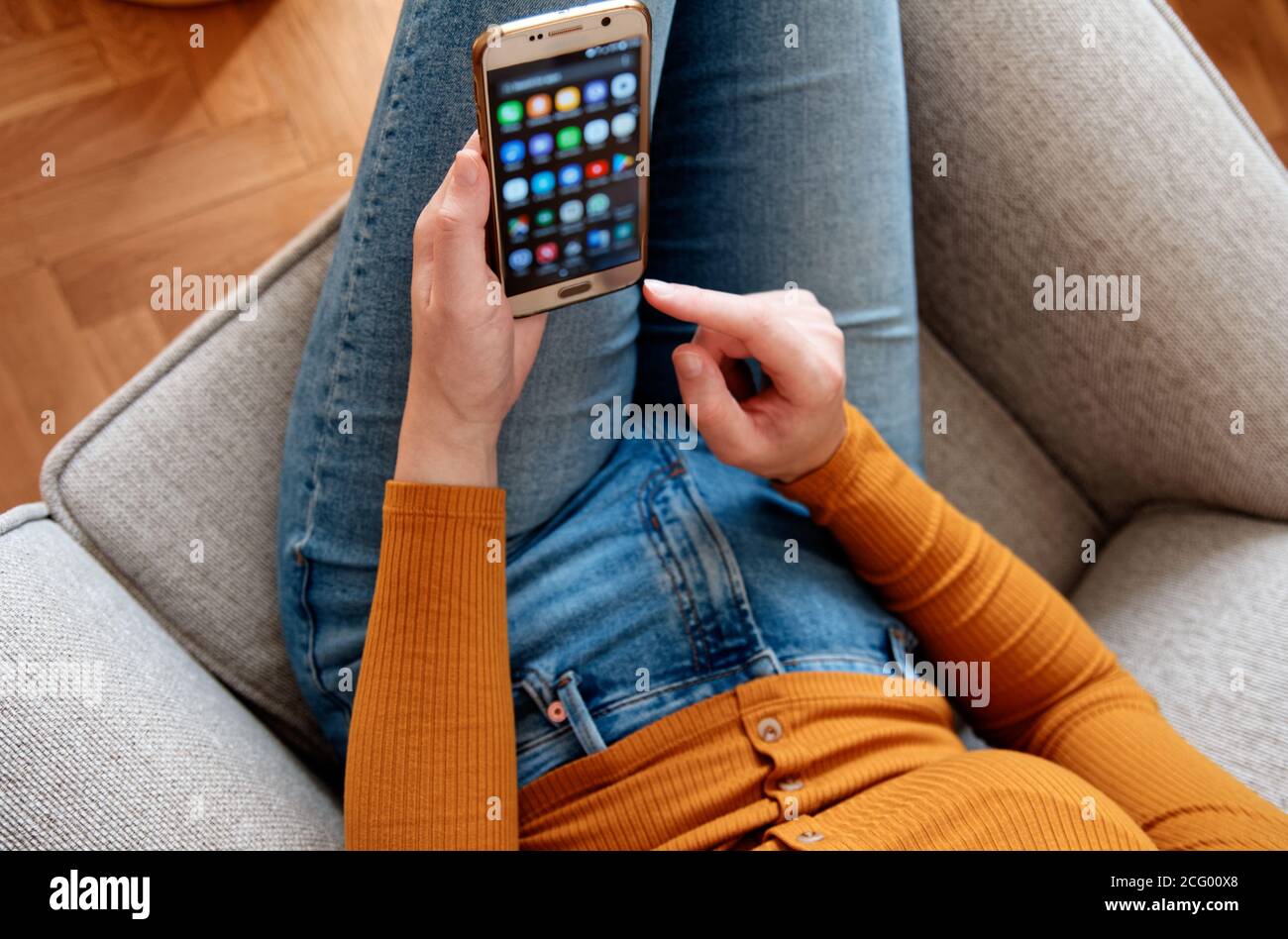 Nahaufnahme der jungen Frau von oben mit Smartphone an Home gelb orange Farben Stockfoto